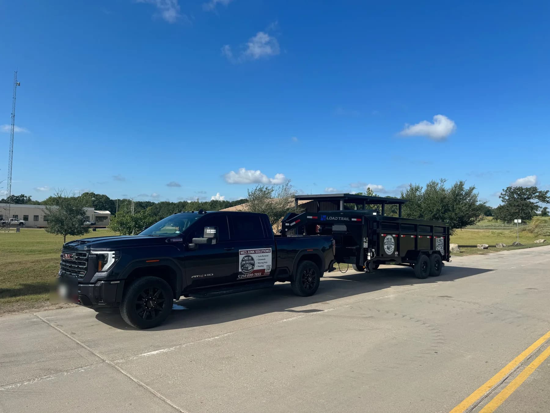 The ME3 Junk Solutions pickup hitched to the gooseneck dump trailer, parked on pavement under a blue sky