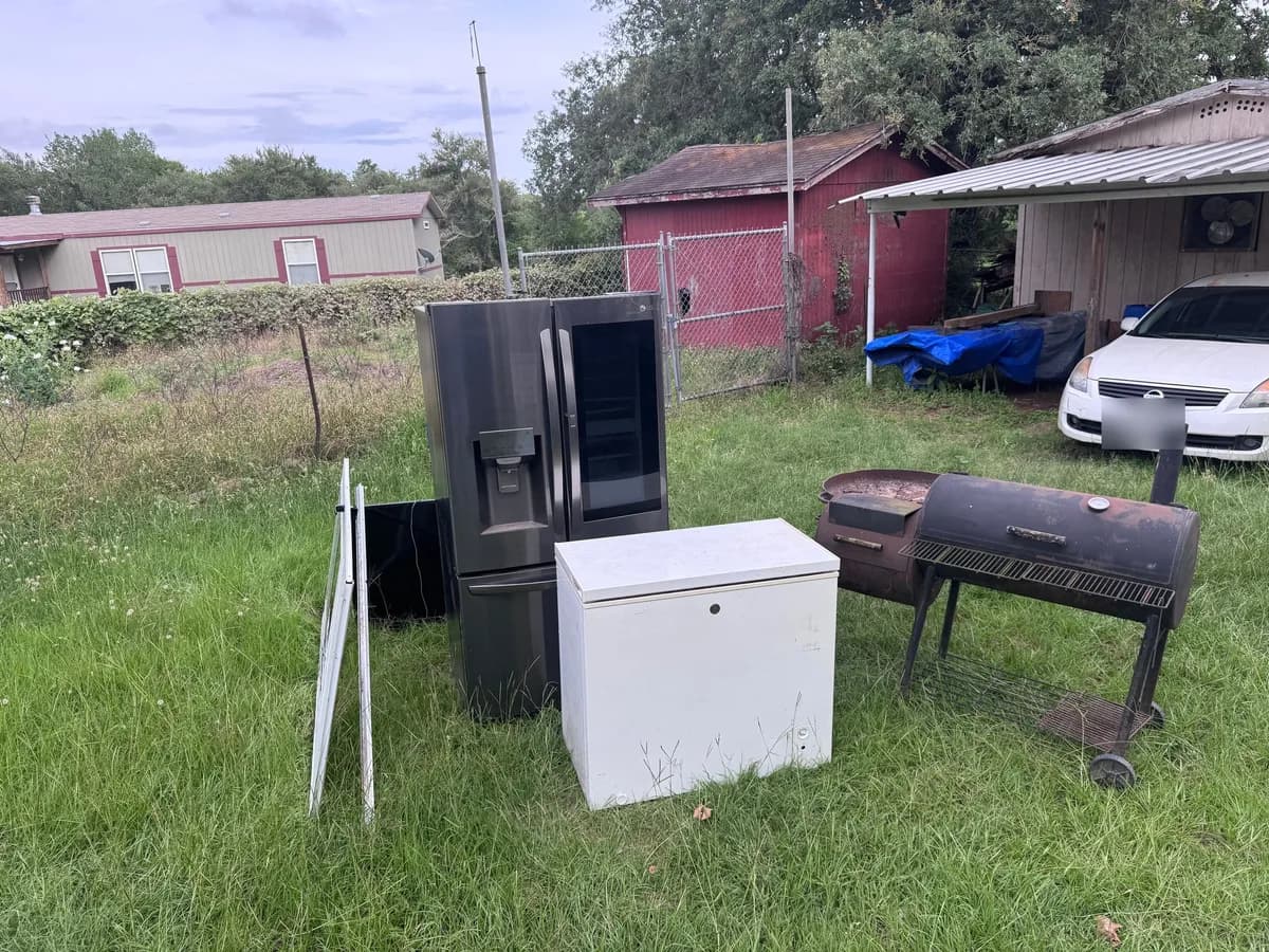 A refrigerator, chest freezer and smoker standing in a yard before ME3 Junk Solutions hauled them off