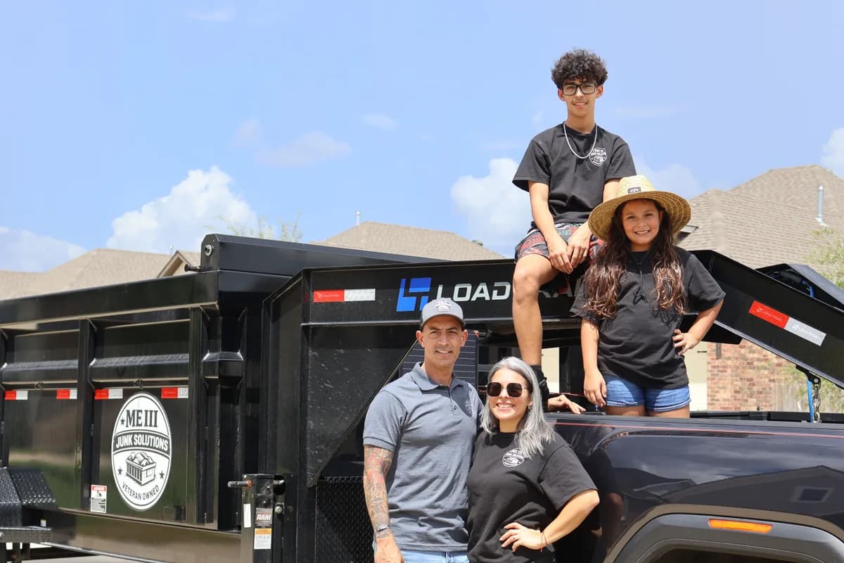 Eddie, his wife, his son and his daughter standing at the ME3 Junk Solutions dump trailer and pickup