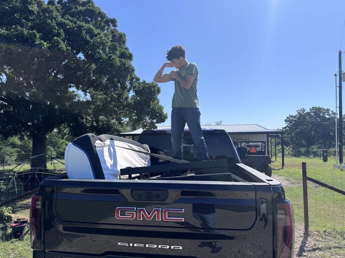 A crew member standing in the loaded ME3 Junk Solutions truck bed on a Brazos Valley job
